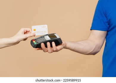 Close up cropped delivery guy employee man hold in hand hold bank payment terminal to process acquire credit card isolated on pastel plain light pastel beige wall background. Copy space advertising