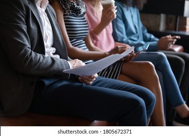 Close Up Cropped Diverse Candidates Sitting In Row, Using Gadgets, Holding Resume Documents, Unemployed Applicants Seekers Waiting For Job Interview In Queue, Employment, Human Resources Concept