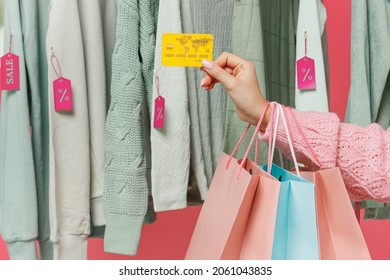 Close Up Cropped Female Costumer Woman Hand Near Clothes Rack With Tag Sale In Store Showroom Holding Package Bags With Purchases After Shopping Credit Card Isolated On Plain Pink Background Studio