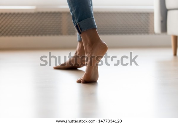 自宅の電気で熱い床に立つ青いジーンズの裸足の女の子の接写 若い女性はつま先立ちで 清潔な床の上にスリッパを置かず 踊りながら歩くのを楽しむ の写真素材 今すぐ編集