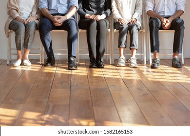 Close up cropped image of diverse people sitting on chairs in row. Five diverse female and male candidates waiting patiently for dream job interview in queue, human resources, recruit process concept.