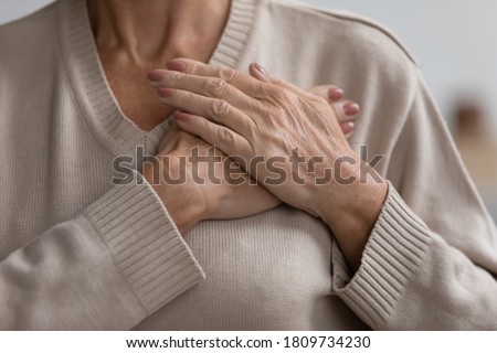 Close up cropped image hopeful grateful mature senior woman keeping hands on chest, mindful middle aged female thanking god and faith, feeling love, gratitude, appreciation, making wish