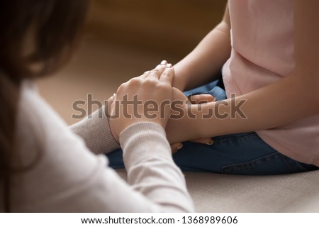 Close up cropped image loving tender mother gently touch hands of little daughter kid showing protection support expressing care and love. Child adoption foster and custody, orphan and new mom concept