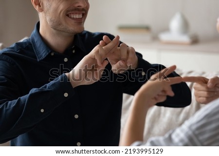 Close up cropped image smiling young deaf dumb family couple using sign language for communication. Happy millennial man and woman with hearing disability showing gestures, expressing feelings.