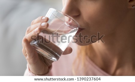 Close up cropped image thirsty woman holding glass drinks still water preventing dehydration, helps maintain normal bowel function and balance of body, skin and health care, healthy lifestyle concept
