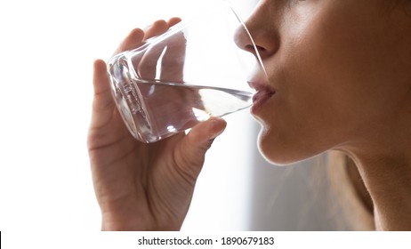 Close up cropped image woman with prefect smooth skin holding glass, drinking still mineral water, preventing dehydration, enjoying daily healthy lifestyle habit, body balance and refreshment - Powered by Shutterstock