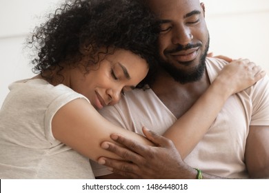 Close up cropped image young attractive african american woman lying on husbands shoulder with closed eyes, embracing beloved man, showing love, support, tenderness. Loving black couple relations.