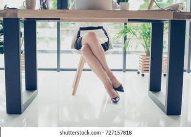 Close Up Cropped Photo Of Attractive Legs Of The Elegant Stunning Business Lady In Dark High Hills Shoes, Skirt, She Is Sitting In The Moden Office, Trendy Chair And Desk, Shuining White Floor