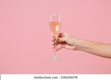 Close Up Cropped Photo Of Female Hold In Hand Glass Of Champagne Isolated On Pastel Pink Wall Background. Copy Space Advertising Mock Up. Valentine's Day Women's Day Birthday Holiday Party Concept