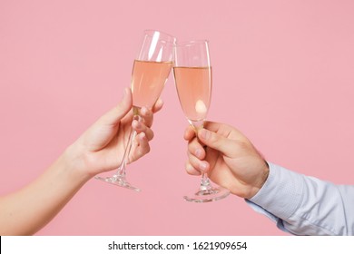 Close up cropped photo of female, male hold in hands glass of champagne isolated on pastel pink background. Copy space advertising mock up. Valentine's Day Women's Day birthday holiday party concept