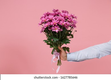 Close Up Cropped Photo Of Male Hold In Hands Bouquet Of Flowers Isolated On Pastel Pink Wall Background. Copy Space Advertising Mock Up. Valentine's Day Women's Day Birthday Holiday Party Concept