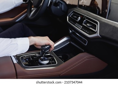 Close Up Cropped Up Photo Shot Hands European Businessman Man Wearing White Shirt Sitting In Car Salon Driving Changes Gears Hold Steering Wheel Automobile Modern Vehicle. Car Sales Driver Concept.