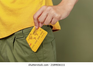 Close up cropped photo shot woman she wear yellow t-shirt hold in hand put into pants pocket mock up of credit bank card isolated on plain olive green khaki background studio. People lifestyle concept - Powered by Shutterstock