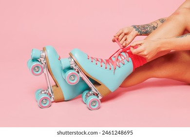Close up cropped photo shot of young woman sit lace up modern blue rollers rollerblading isolated on plain pastel light pink color wall background. Summer season hobby sport lifestyle leisure concept