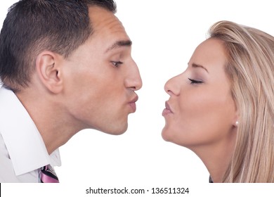 Close Cropped Portrait Of The Faces Of A Young Man And Woman Preparing To Kiss Leaning Towards Each Other With Their Lips Puckered, Isolated On White