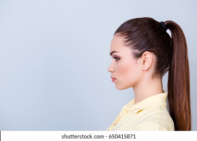 Close Up Cropped Profile Portrait Of Young Lady In Yellow Tshirt With Ponytail, Serious Face On Pure Background With Copy Space