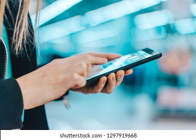 Close Up Cropped Shot Of Female Hands Holding Mobile Phone Making Online Purchases In The Internet Stop. Blurred Futuristic Background.