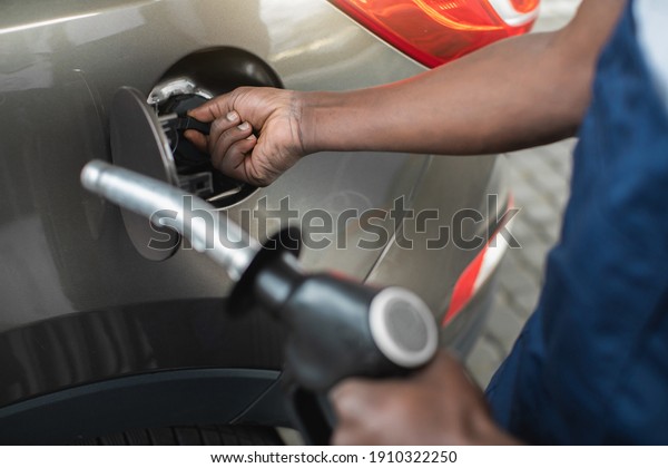 Close up cropped shot of a gas station worker\'s\
hands with filling gun, ready to refueling the car with gas or\
petrol at a gas station.