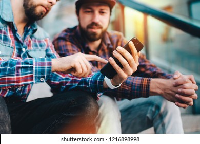 Close Up Cropped Shot Of Two Friends Betting In Online Gambling Application Using Mobile Phone. Men Watching Online Broadcast Waiting For Lottery Winners Announcement.