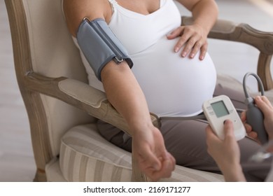 Close Up Cropped Shot Unknown Pregnant Woman Sits On Armchair While Doctor Measuring Blood Pressure Use Digital Tonometer. Hypertension During Severe Pregnancy, Health Check Up, Prenatal Care Concept