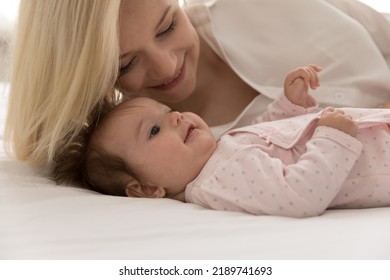Close up cropped shot young beautiful mother and cute newborn daughter in bodysuit lying resting on bed looking happy spend priceless time together. Pure love, maternity, family bond, adoption - Shutterstock ID 2189741693
