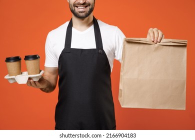 Close Up Cropped Shot Young Man Barista Bartender Barman Employee In Apron White T-shirt Work In Coffee Shop Hold Delivery Cups Craft Bag Mock Up Isolated On Orange Background Business Startup Concept