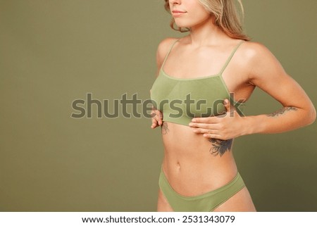 Close up cropped side view young lady woman with slim skinny body perfect skin wearing top bra lingerie stand put hand on breast chest isolated on plain green background. Lifestyle diet fit concept