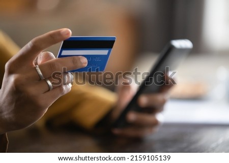 Close up cropped view African female do online shopping use credit card and smart phone. Cashless payment, easy quick money transfer using mobile application, secure e-pay, e-bank app usage concept
