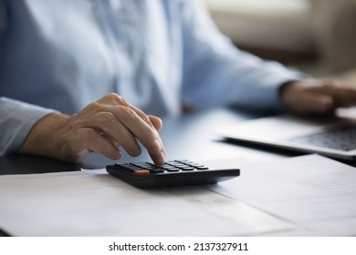 Close up cropped view woman sit at desk use calculator and laptop, calculates domestic expenditures, manage monthly finance, makes household bills payment through e-bank. Money saving, economy concept