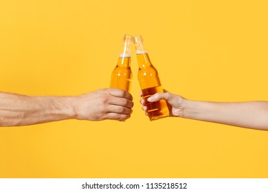 Close up cropped of woman and man two hands horizontal holding lager beer glass bottles and clinking isolated on yellow background. Sport fans cheer up. Friends leisure lifestyle concept. Copy space - Shutterstock ID 1135218512