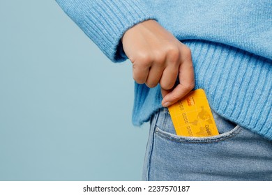 Close up cropped woman wearing knitted sweater hold in hand put into pocket mock up of credit bank card isolated on plain pastel light blue cyan background studio portrait. People lifestyle concept - Shutterstock ID 2237570187