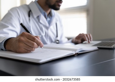 Close Up Cropped Young African American Male Doctor Handwriting Notes In Paper Journal, Managing Appointments In Registration Book, Prescribing Illness Treatment, Doing Paper Work In Clinic Office.