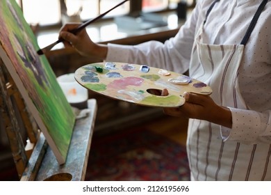 Close up cropped young male artist holding palette with mixed acrylic paints, involved in creating artwork on canvas, improving art painting skills, enjoying hobby activity in modern studio or home. - Powered by Shutterstock