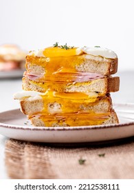 Close Up Of The Croque Madame Fried Cheese Sandwich With Runny Egg Dripping Over The Sliced French Sandwich With Béchamel Sauce