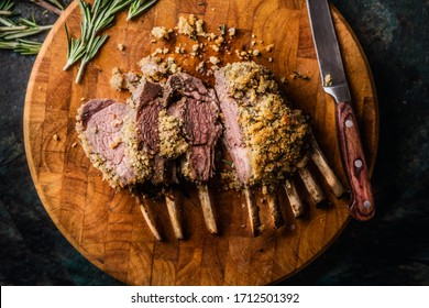 Close up of crusted lamb ribs cutlets with bone rar medium roasted on wooden cutting board with knife and herbs. Top view. Meat food - Shutterstock ID 1712501392