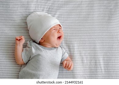 Close Up Of A Crying Newborn Laying On A Striped Gray Nappy. Hangry Baby. Infantile Colic. Baby Care