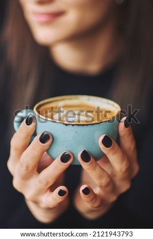 Close up Cup of coffee latte in coffee shop.Female hands holding a cup of coffee cup with heart shaped latte art foam