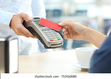 Close Up Of A Customer Hand Paying With A Contactless Credit Card Reader In A Bar Interior