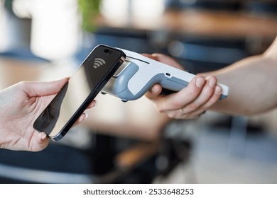 Close Up of a Customer Making a Secure Contactless Online Payment Using a Smartphone with a Credit Card Banking NFC App. Modern Shopper Buying Organic Fruits and Vegetables From a Farmers Market Stall - Powered by Shutterstock