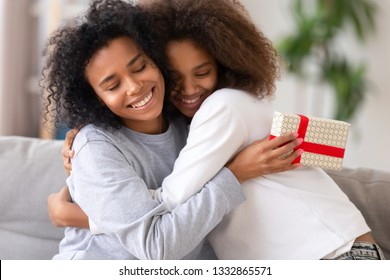 Close up cute african teen daughter congratulate mom with mother day, relative people embracing, mom feels gratitude. Celebration of anniversary or birthday, family life events and best wishes concept - Powered by Shutterstock