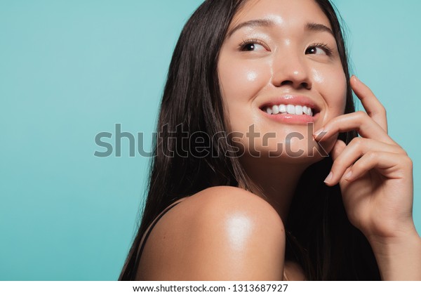 青の背景に赤い肌をしたかわいいアジアの女の子の接写 新鮮な健康的な肌をした女の子の美しい顔 の写真素材 今すぐ編集