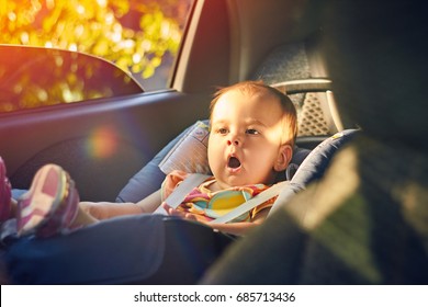 Close Up Cute Baby Sitting In Modern Car Seat. Child New Born Traveling Safety On The Road. Safe Way To Travel Fastened Seat Belts In A Vehicle With Young Kids. Trip With An Infant.