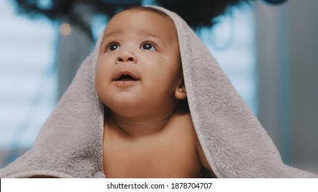 Close Up Of Cute Black Baby With Head Covered With Fluffy Towel Christmass Tree In The Background. High Quality Photo