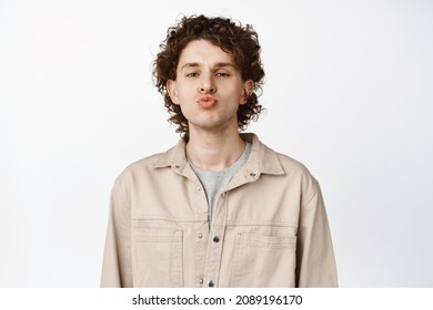 Close Up Of Cute Curly Guy Kissing, Pucker Lips And Looking Funny At Camera, White Background