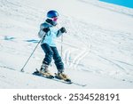 Close up Cute little brave girl ski downhill on slope in winter ski resort. Active lifestyle winter holidays with kids concept