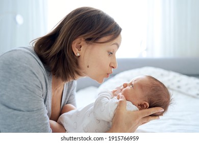 Close Up Of Cute One Months Old Baby Boy Lying On Bed And Playing With His Mum. Mum Talking To Son And Cuddling Him. High Quality Photo