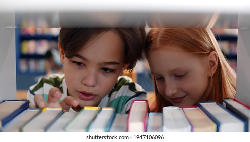 Close Up Of Cute Preteen Kids Choosing Books In School Library. Portrait Of Schoolchildren Selecting Book On Shelf In Modern Bookstore