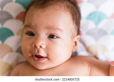 Close Up Of Cute Smiling Latino Baby Girl In Bed With Morning Light. Waking Up In Bed. Healthy Hispanic Baby With Warm Natural Light