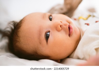 Close Up Of Cute Smiling Latino Baby Girl In Bed With Morning Light. Waking Up In Bed. Healthy Hispanic Baby With Warm Natural Light