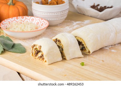 Close Up Of Cutting Board With Rolled And Cut Unbaked Beef Pumpkin Pinwheels